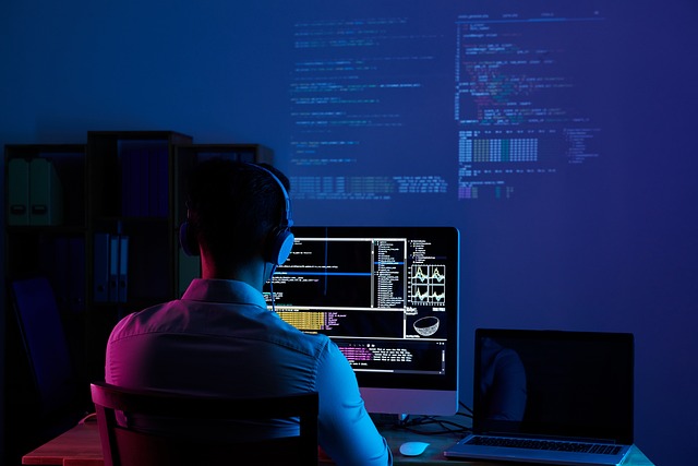 In this image a web developer is working on computer, opened code editor on large screen, and also have laptop on the right and in front have larger screen. Along with all of this, web developer pluged headphones. Now the context of this image here, is that how many things a web developer have to go through. This is night time in image. 